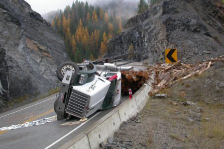 Logging truck rolls over on sharp curve